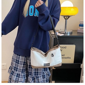 Dettaglio della borsa Hobo bianca e kaki con etichetta del marchio e tracolla in nylon