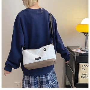 Dettaglio della borsa tote bicolore in tela con tracolla regolabile e toppa logo