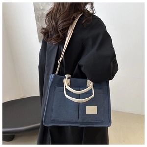 Detail view of large capacity dark blue canvas tote bag with adjustable cream shoulder strap