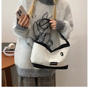Dettaglio della borsa tote bicolore con placca logo e anello a D decorativo laterale