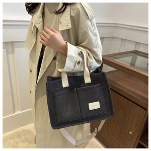 Detail of dark gray canvas tote bag featuring double front pockets and woven straps