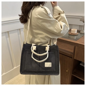 Minimalist black canvas tote bag with multiple pockets and white handles for daily use