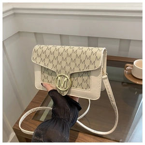 Dettaglio borsa a tracolla beige con motivo monogramma e fibbia dorata con logo M in metallo