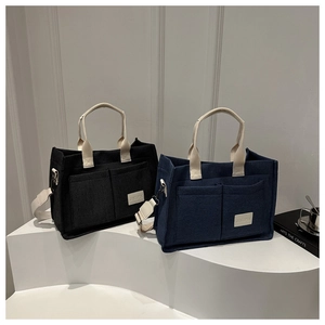 Minimalist canvas tote bags in black and navy with dual front pockets and shoulder straps
