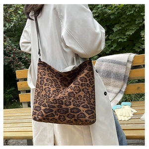 Detailed view of the leopard print hobo bag with leather strap worn over an autumn coat