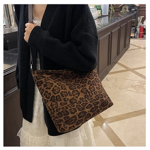 Detailed view of leopard print faux suede tote bag worn by a model in a cozy setting