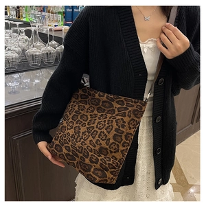 Chic leopard print tote bag with brown straps styled on shoulder in a bar setting
