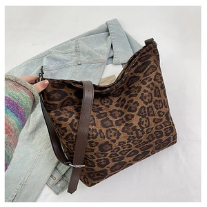 Detail of hobo bag featuring leopard print fabric and adjustable brown leather strap