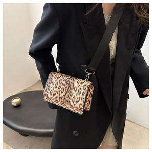 Leopard print crossbody bag with wide black strap shown on a model in a black suit
