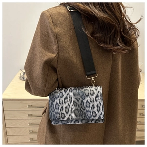 Leopard print crossbody bag with wide strap worn by a model in a warm indoor setting