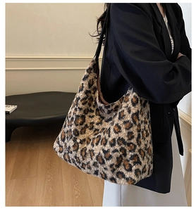 Side view of plush leopard print tote bag with black strap on a model shoulder