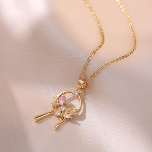 Minimalist gold necklace with pink stone pendant on elegant silk champagne background