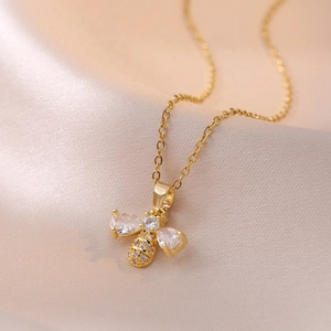 Golden bee pendant necklace with zircon stones on elegant champagne silk background