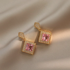 Elegant gold earrings with pink square gemstones and pavé crystals on champagne silk