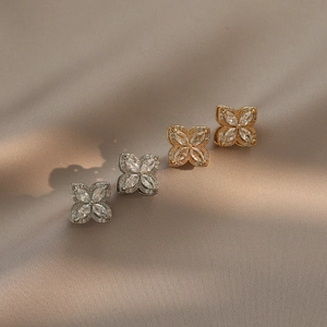 Rotating four-leaf clover stud earrings with marquise cubic zirconia on beige silk cloth