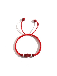 Macro detail of red hand-woven lucky rope bracelet with Pixiu charm and silver beads