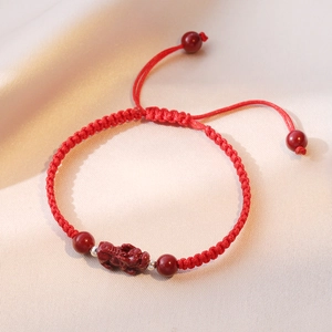 Close-up of red braided bracelet with Cinnabar Pixiu charm and adjustable drawstring