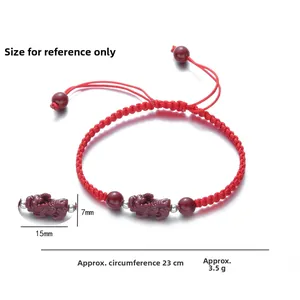 Macro detail of red woven bracelet featuring a Pixiu charm and silver spacer beads