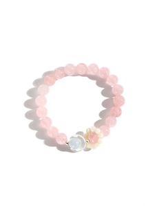 Detail of pink crystal beaded bracelet with moon charm and delicate flower accent