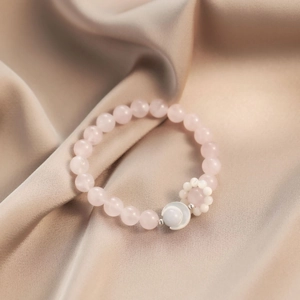 Elegant natural rose quartz moon bracelet with silver beads on champagne silk background