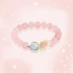 Pink quartz bead bracelet with a crescent moon pendant and soft bokeh background