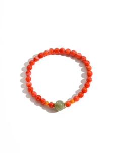 Gros plan d'un bracelet en perles d'agate rouge avec perle de jade et accents dorés