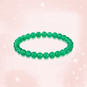 Macro shot of green agate bead bracelet on pink background with reflections