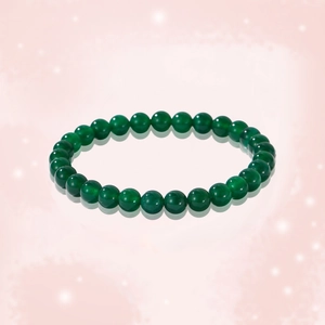 Natural dark green jade bead bracelet on reflective pink background with soft lighting
