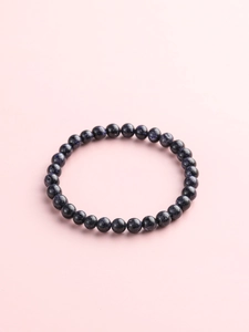 Macro shot of blue sandstone beaded bracelet with shimmering starry effect on pink background