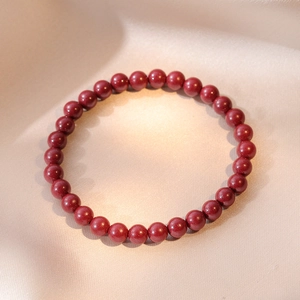 Handcrafted cinnabar beaded bracelet with deep red natural stones on silk background