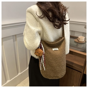 Detail of soft brown fuzzy bucket bag with plush dog charm and woven stripe tassel