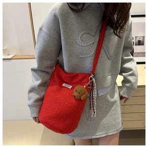 Detail of red teddy fleece bucket bag with plush charm on casual grey sweatshirt