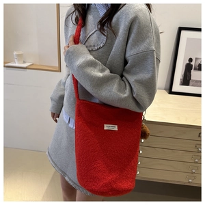 Close-up of fluffy red wool bucket bag with brand label and plush ball pendant charm