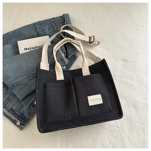 Deep grey canvas tote bag with cream straps and adjustable shoulder strap on white fabric
