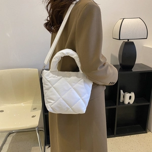 French minimalist white quilted bucket bag with padded texture and adjustable shoulder strap