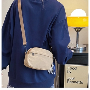 Dettaglio della borsa a tracolla beige in nylon con ciondolo a forma di orso a quadretti