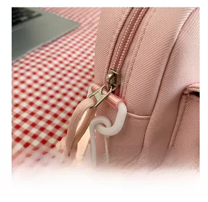 Detailed close-up of smooth silver zipper and pink nylon fabric on a small crossbody bag