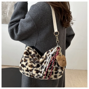 Détail du sac cabas en fausse fourrure léopard avec charme d'ours et bandoulière blanche