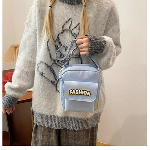 Close-up of light blue crossbody bag featuring a fuzzy Fashion patch and adjustable strap