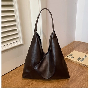 Detail of a dark brown PU leather hobo bag with unique triangular fold design and texture