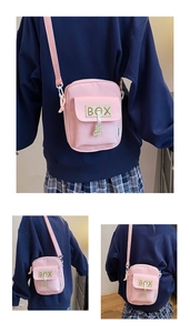 Detailed view of pink canvas crossbody bag with cute bear charm and adjustable strap