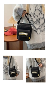 Detail view of black crossbody phone bag with yellow FASHION patch and zip closure