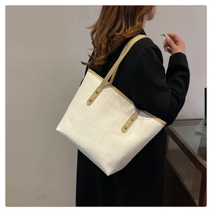 Dettaglio della grande borsa tote bianca con manici kaki e borchie in metallo vintage