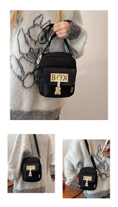 Detail of black canvas crossbody bag with BOX patch and cute bear pendant charm