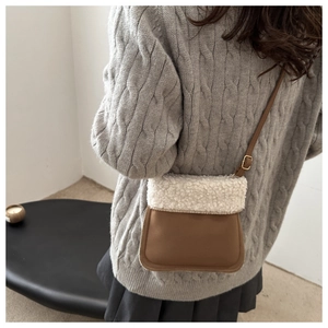 Detail of plush faux shearling trim on brown suede crossbody bucket bag for winter