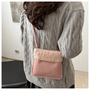 Détail du sac seau rose en fausse fourrure porté sur un pull en maille grise