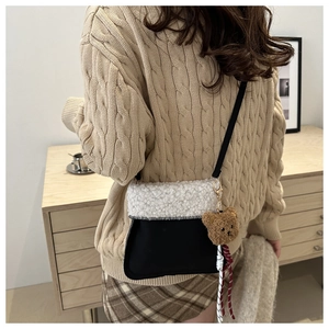 Close-up of fluffy sherpa and black suede bucket bag with a cute brown bear charm