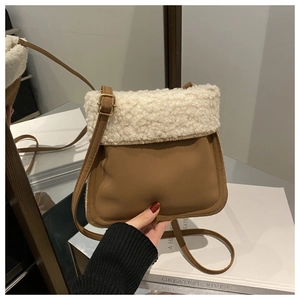Detail of faux shearling bucket bag with brown leather strap and gold buckle adjustment
