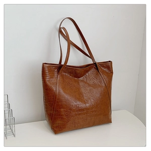 Detail of caramel crocodile embossed leather tote bag showing glossy texture and stitching