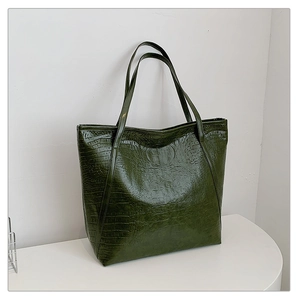 Detail of dark green tote bag featuring luxury crocodile texture and spacious opening
